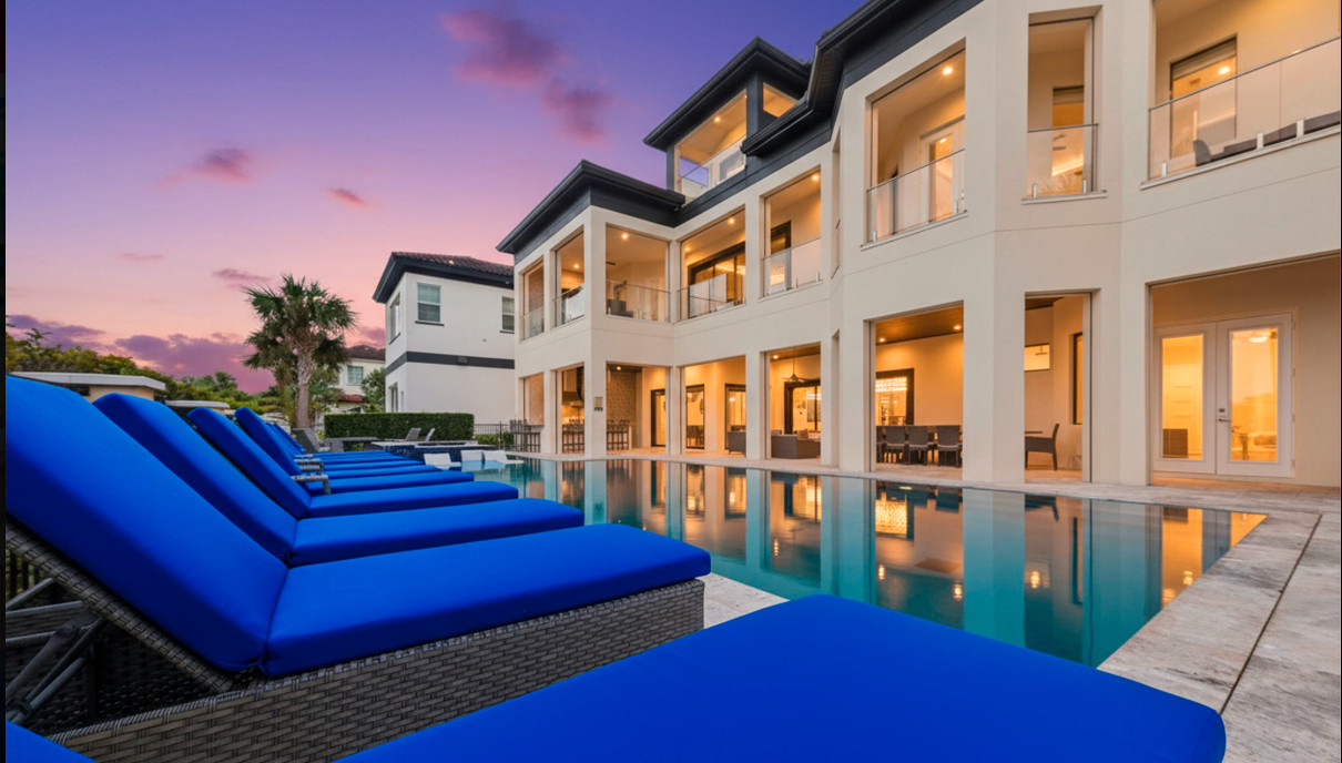 Luxury vacation rental Orlando – private pool villa with blue lounge chairs at sunset by Jeeves by Casago